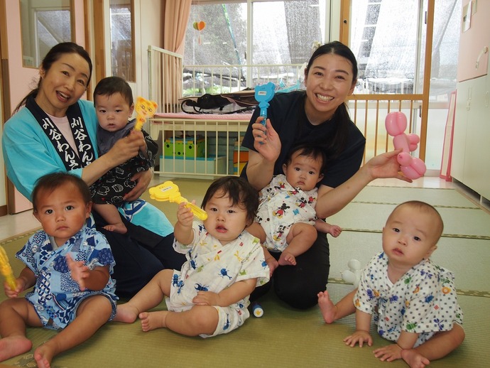 0歳児が保育者と夏まつりを楽しんでいる写真