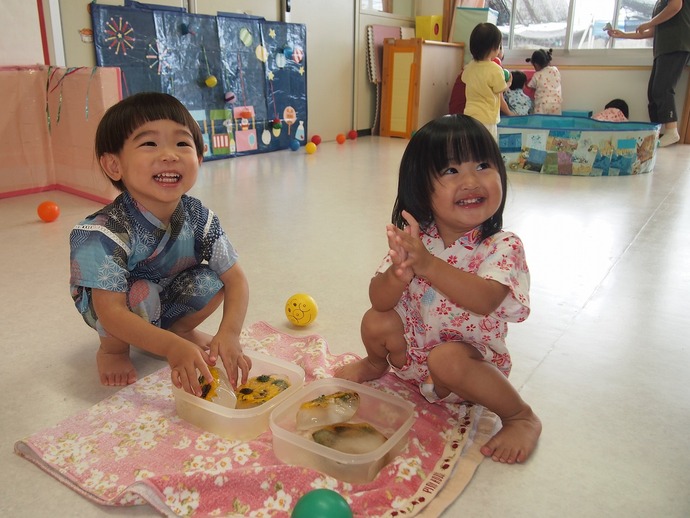 1歳児が夏まつりで氷遊びを楽しんでいる写真