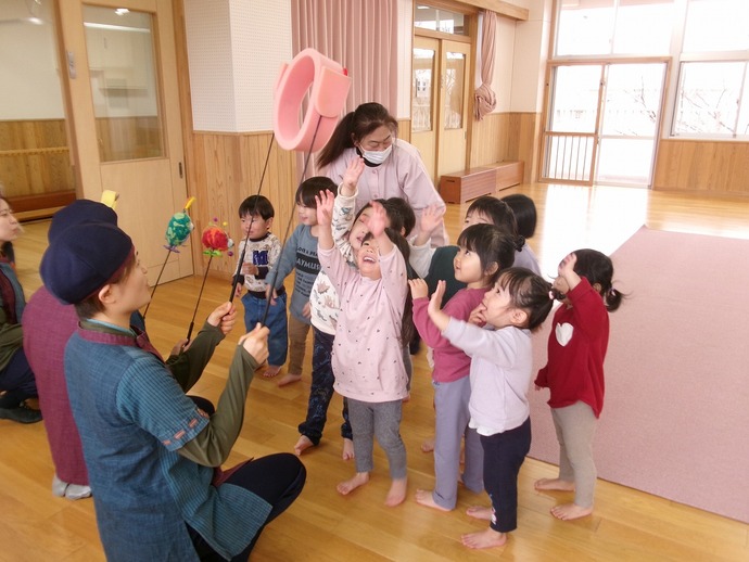 2歳児が人形劇団むすび座の人たちと触れ合っている写真