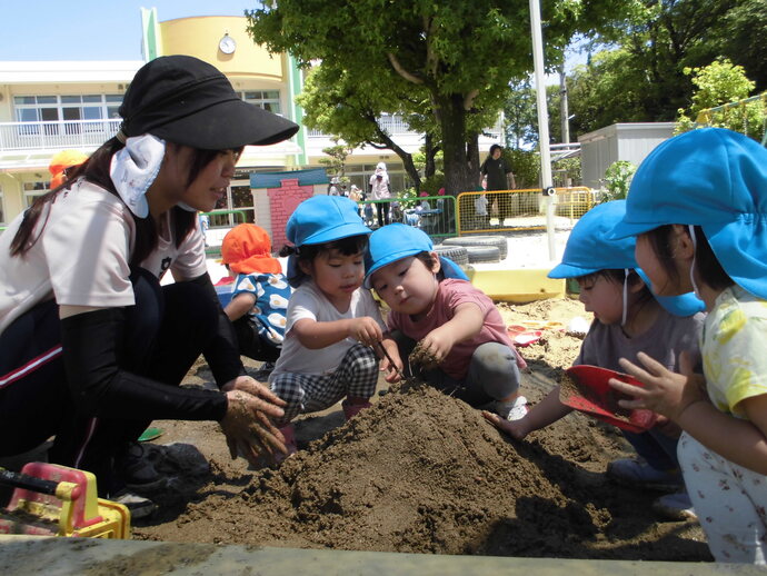 2歳児　友達と砂場で山を作っている写真
