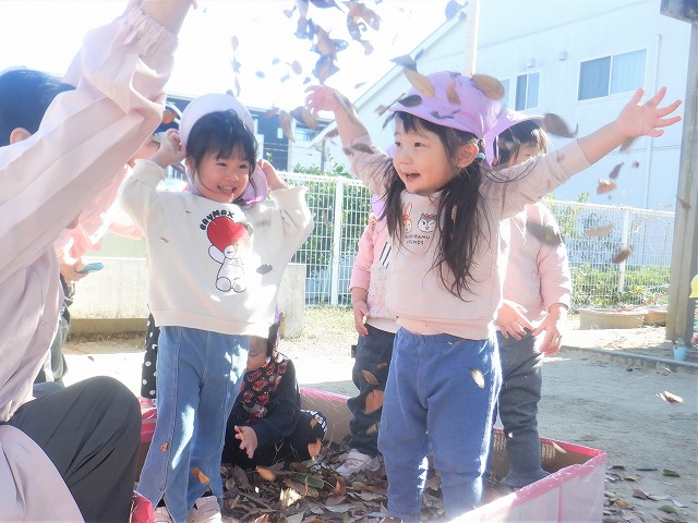 写真:落ち葉で遊ぶ2歳児