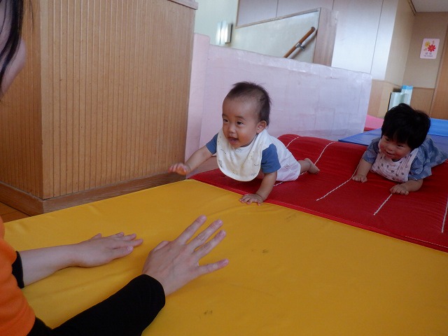 写真:マットの上をはいはいする0歳児の様子
